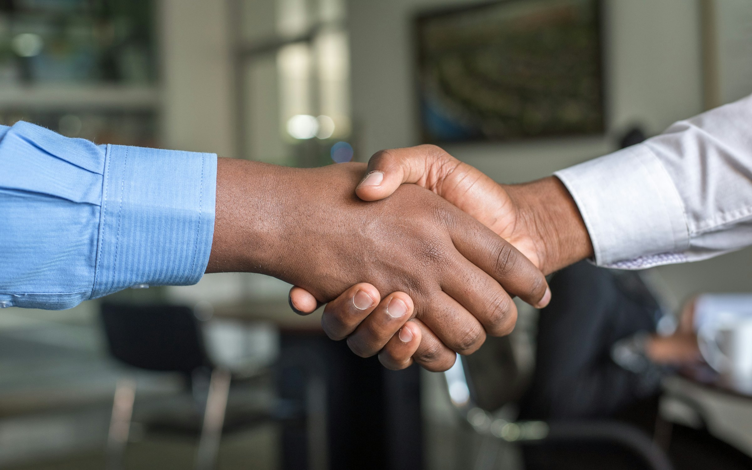 Two professionals shaking hands across a meeting table